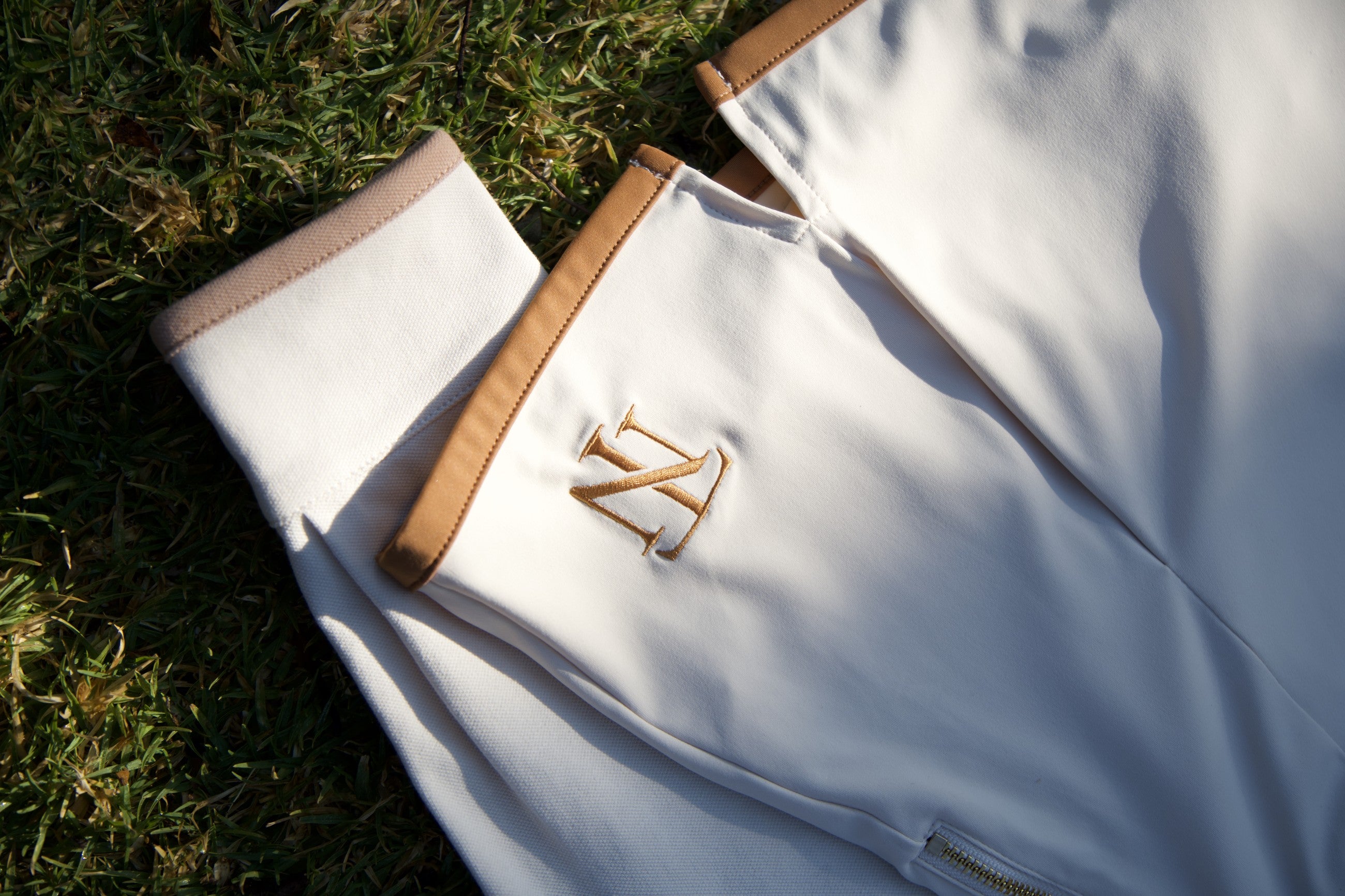 Tee Noir — gold TN monogram and camel trim detail on cream performance fabric